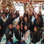 A group of young adults smiling inside a festively decorated lobby.